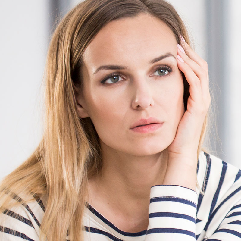 Woman with auditory neuropathy holding her head.