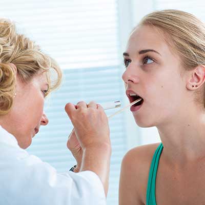 ENT examining the sores in a woman's mouth. 